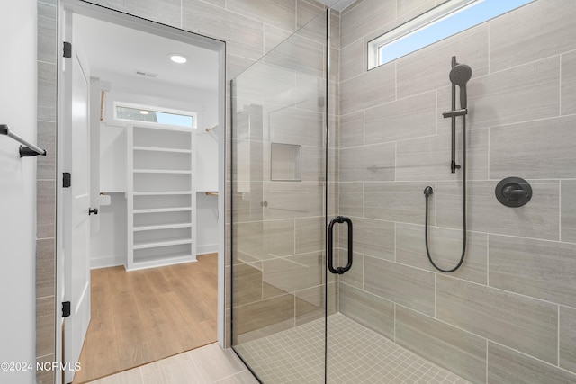 bathroom featuring a shower with door, wood-type flooring, and a wealth of natural light