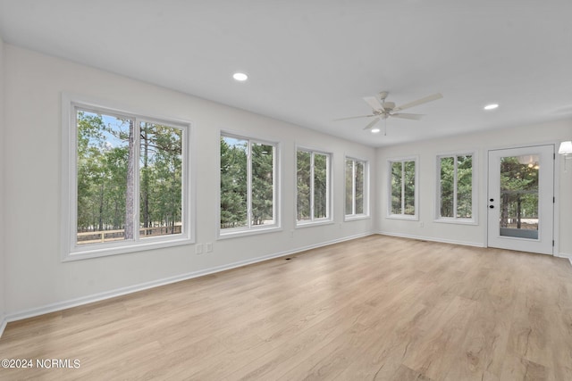 unfurnished sunroom featuring ceiling fan and plenty of natural light