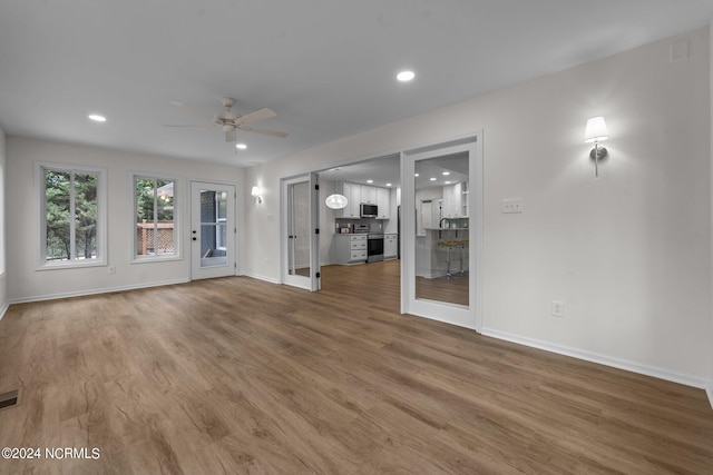 unfurnished living room with wood-type flooring and ceiling fan