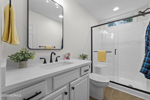 bathroom with vanity, a shower with shower door, hardwood / wood-style floors, and toilet