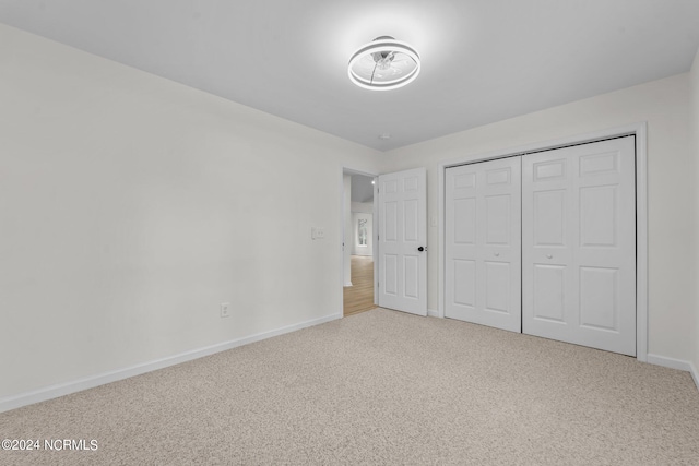 unfurnished bedroom with light carpet and a closet