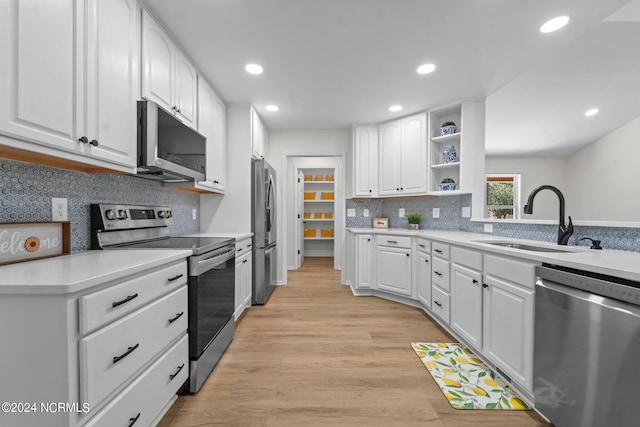 kitchen with tasteful backsplash, appliances with stainless steel finishes, sink, light wood-type flooring, and white cabinets