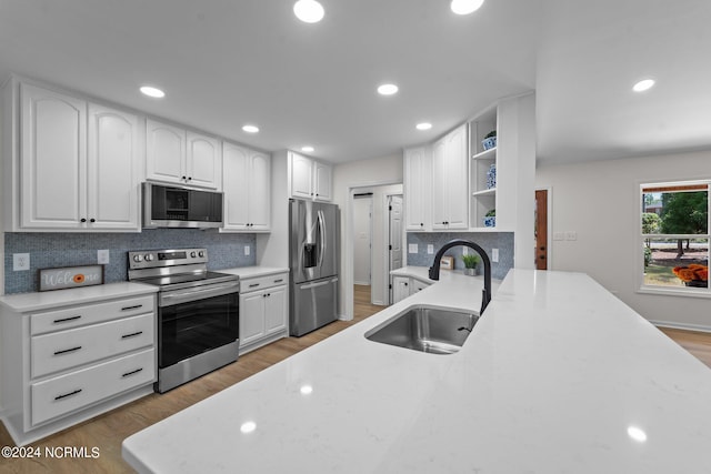 kitchen featuring decorative backsplash, white cabinets, hardwood / wood-style floors, appliances with stainless steel finishes, and sink