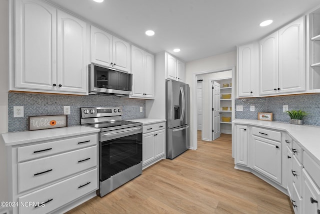 kitchen with decorative backsplash, white cabinetry, stainless steel appliances, and light wood-type flooring