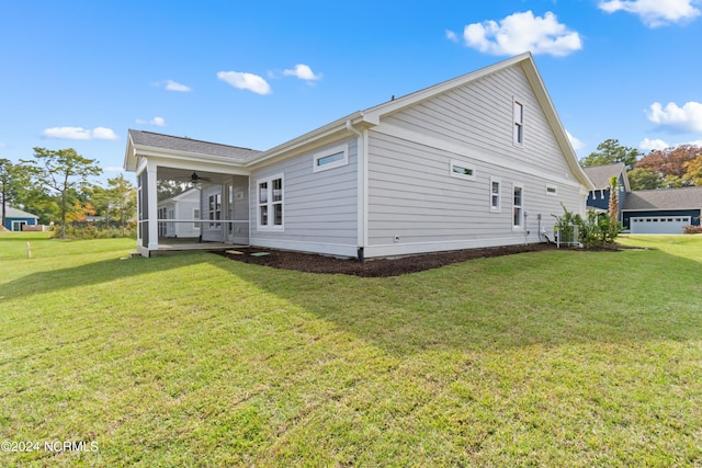 rear view of property featuring ceiling fan, a yard, and a sunroom