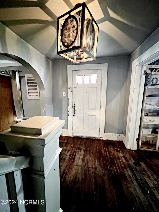 entryway with an inviting chandelier and dark wood-type flooring