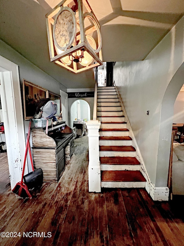 stairs with an inviting chandelier and hardwood / wood-style flooring