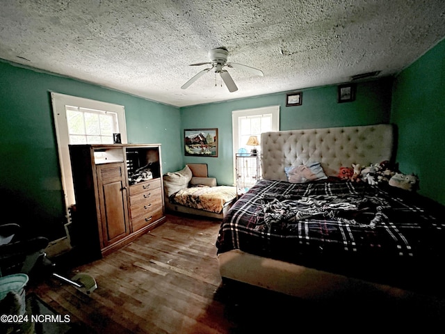 bedroom featuring ceiling fan, hardwood / wood-style floors, and a textured ceiling