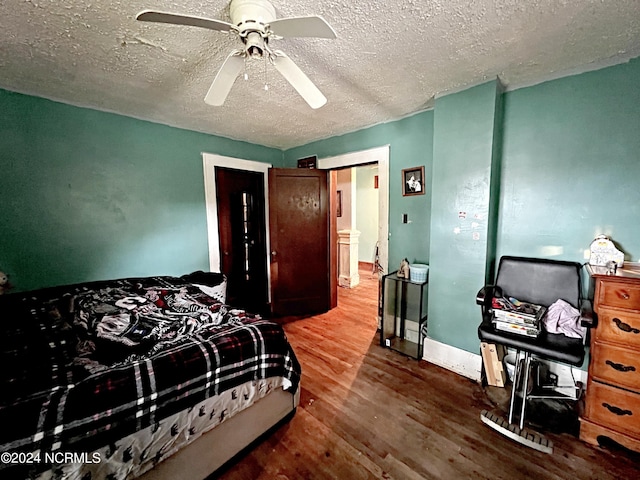 bedroom with ceiling fan, hardwood / wood-style flooring, and a textured ceiling