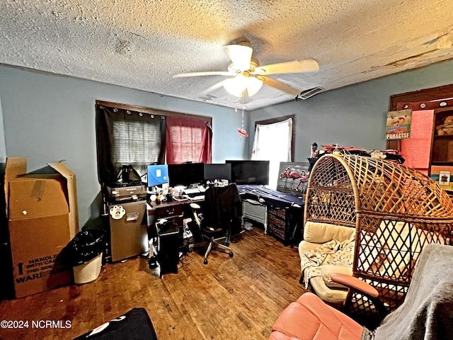 home office with a textured ceiling, wood-type flooring, and ceiling fan