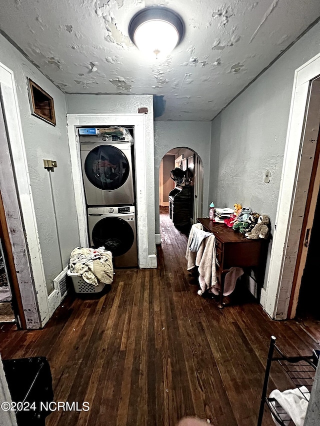 hall featuring stacked washer and dryer and dark wood-type flooring