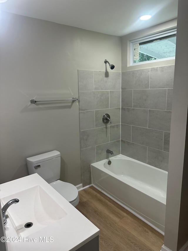 full bathroom featuring hardwood / wood-style floors, tiled shower / bath, toilet, and vanity