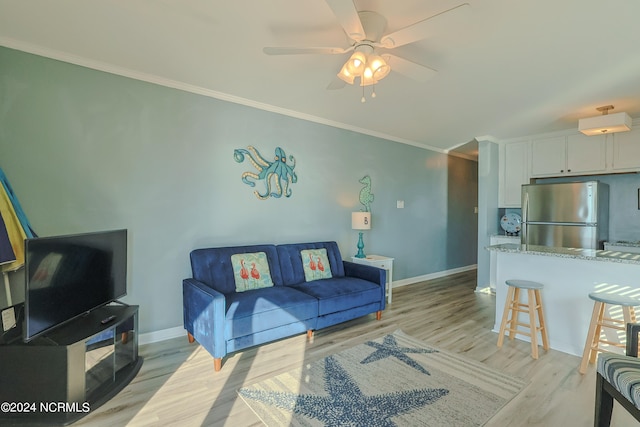 living room with ornamental molding, light hardwood / wood-style floors, and ceiling fan