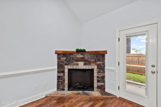 unfurnished living room with a stone fireplace, lofted ceiling, and hardwood / wood-style floors