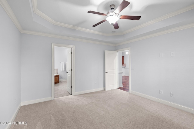 unfurnished bedroom featuring light carpet, a raised ceiling, ensuite bathroom, crown molding, and ceiling fan