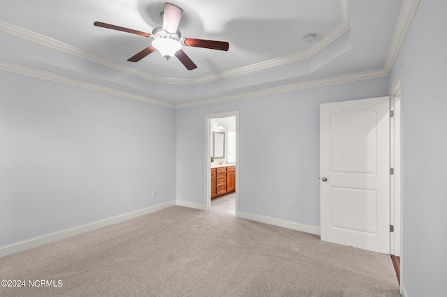 empty room featuring ceiling fan, a tray ceiling, light carpet, and ornamental molding