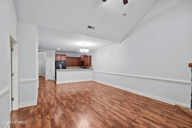 unfurnished living room with ceiling fan with notable chandelier and dark wood-type flooring