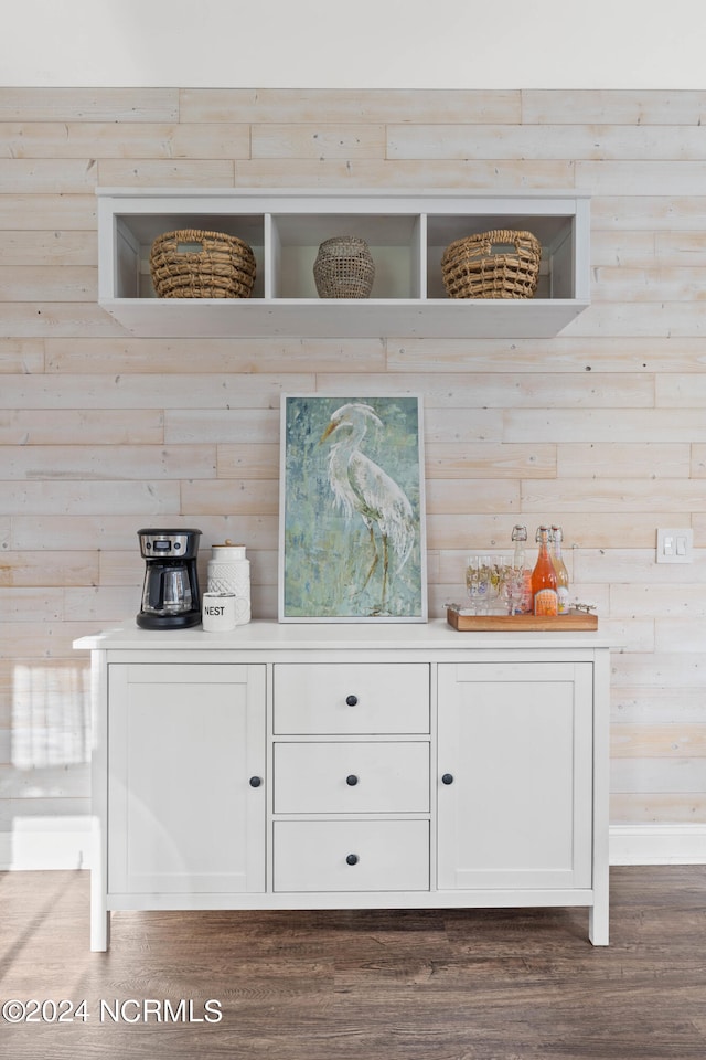 bar with white cabinets, dark hardwood / wood-style floors, and wood walls