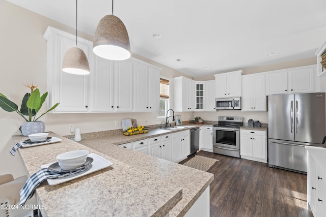 kitchen featuring white cabinetry, sink, dark wood-type flooring, stainless steel appliances, and pendant lighting