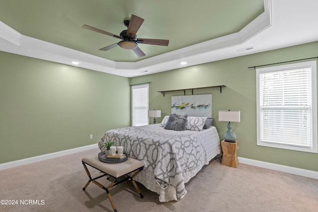 bedroom featuring light carpet, a raised ceiling, and ceiling fan