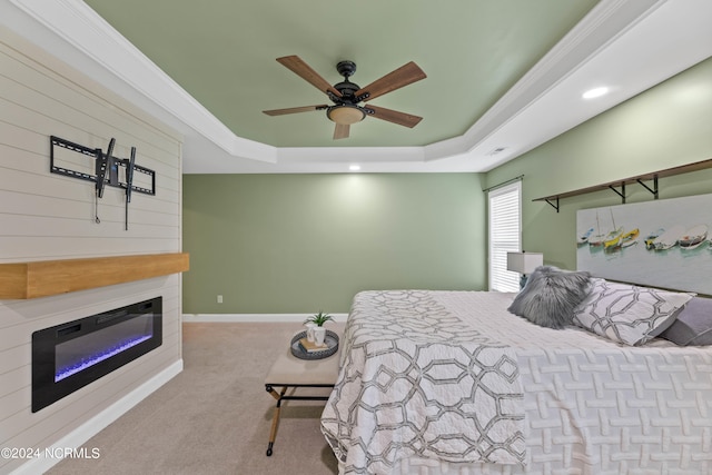 bedroom with a tray ceiling, crown molding, ceiling fan, and light colored carpet