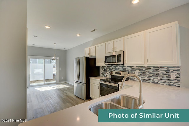 kitchen featuring a sink, stainless steel appliances, light countertops, a notable chandelier, and backsplash