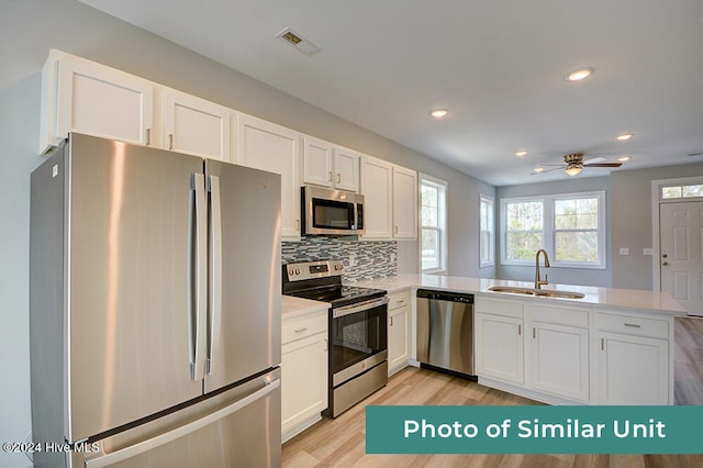 kitchen with light wood finished floors, a sink, visible vents, a peninsula, and appliances with stainless steel finishes