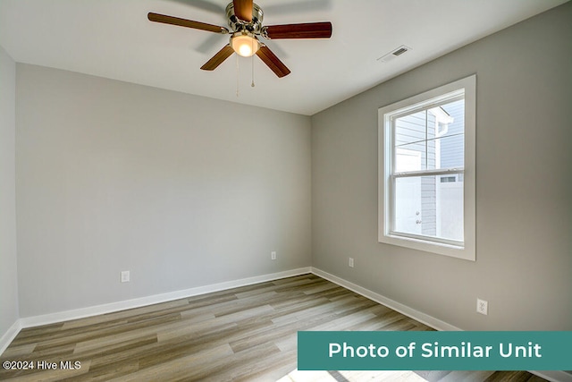spare room featuring baseboards, visible vents, wood finished floors, and a ceiling fan