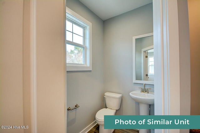 bathroom featuring toilet, baseboards, and plenty of natural light
