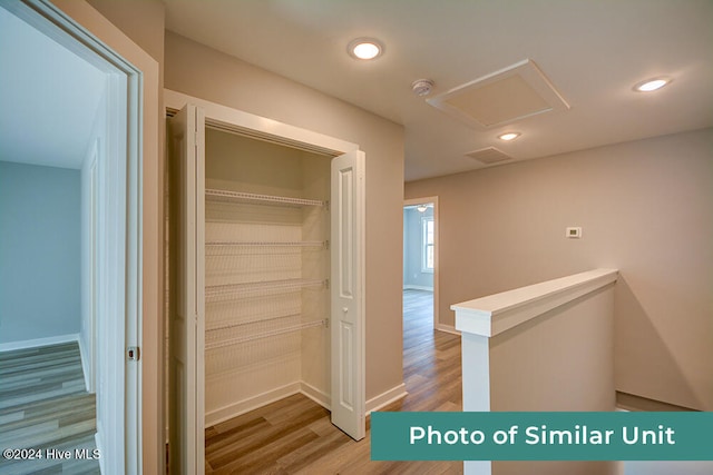 hallway with attic access, recessed lighting, an upstairs landing, baseboards, and wood finished floors