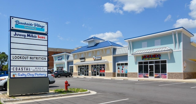 exterior space with a standing seam roof, metal roof, parking, and brick siding