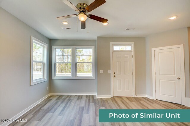 kitchen featuring white cabinets, decorative backsplash, ceiling fan, light wood-type flooring, and appliances with stainless steel finishes