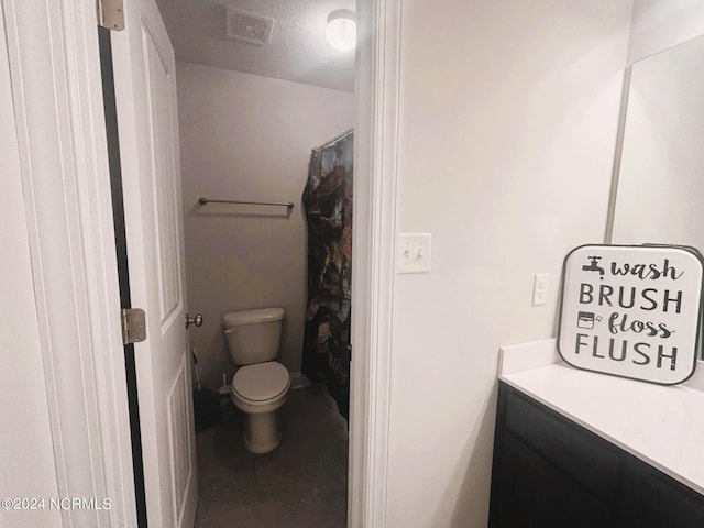 bathroom featuring vanity, a textured ceiling, and toilet