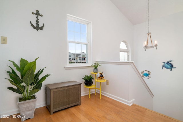 sitting room featuring light wood-type flooring, high vaulted ceiling, an inviting chandelier, and plenty of natural light