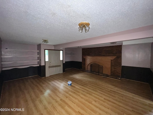 unfurnished living room featuring wood-type flooring, a textured ceiling, and a fireplace