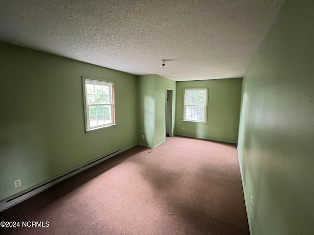 empty room with a textured ceiling, carpet flooring, and a baseboard heating unit