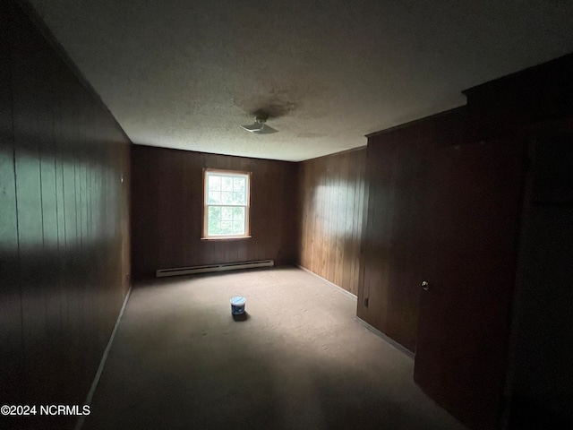 carpeted spare room featuring a baseboard heating unit and wood walls