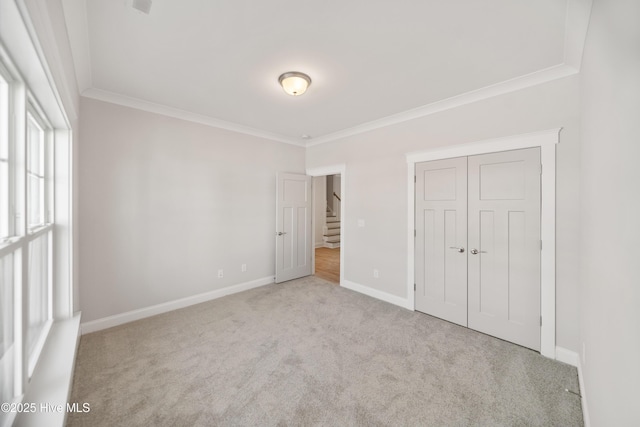 unfurnished bedroom with ornamental molding, light carpet, and baseboards