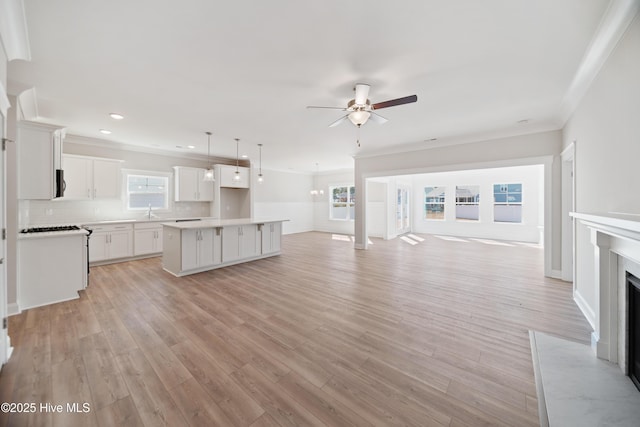 kitchen with pendant lighting, light countertops, open floor plan, white cabinetry, and a kitchen island