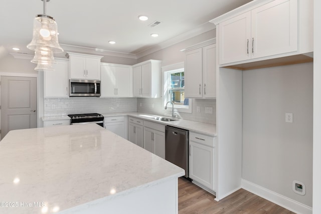 kitchen featuring white cabinets, appliances with stainless steel finishes, hanging light fixtures, light stone countertops, and a sink