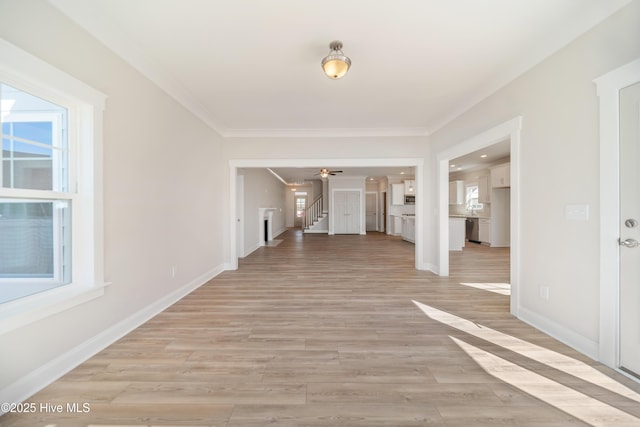 unfurnished room featuring light wood-style floors, baseboards, stairway, and ornamental molding