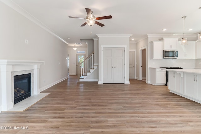 kitchen with white cabinetry, stainless steel microwave, light countertops, and open floor plan