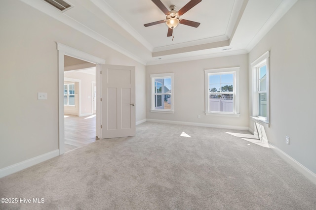 unfurnished room featuring baseboards, visible vents, light colored carpet, a tray ceiling, and crown molding