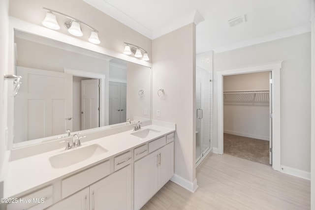 bathroom featuring a stall shower, a walk in closet, visible vents, and a sink