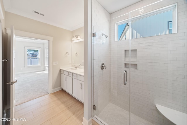 full bathroom with crown molding, a sink, a shower stall, and double vanity