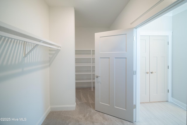 walk in closet featuring light colored carpet