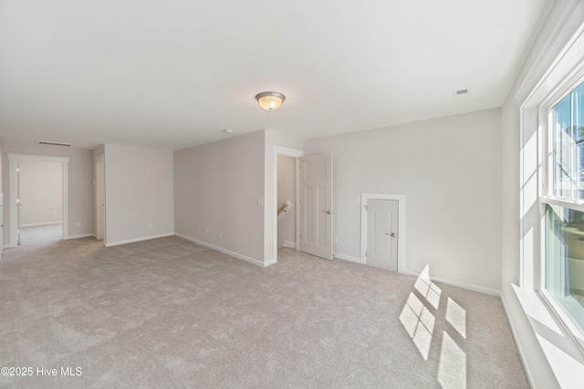 unfurnished room featuring light carpet and baseboards