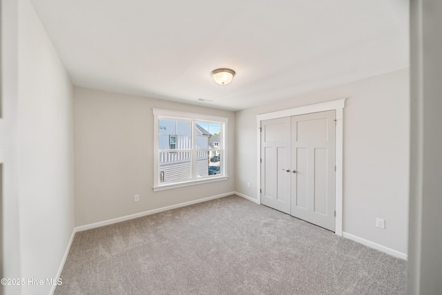 unfurnished bedroom with baseboards, a closet, and light colored carpet