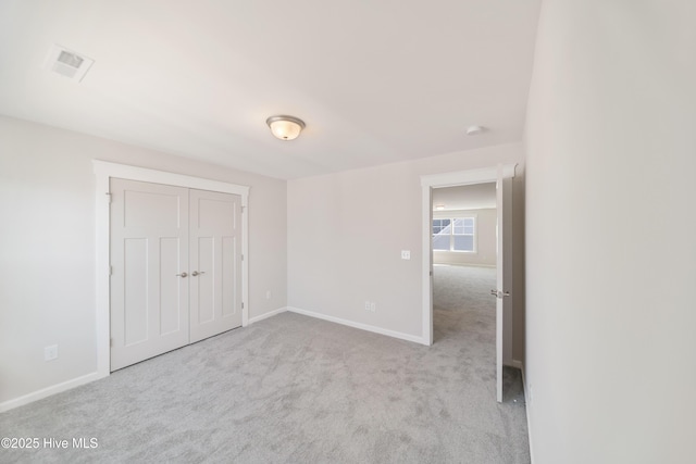 unfurnished bedroom featuring a closet, light carpet, visible vents, and baseboards