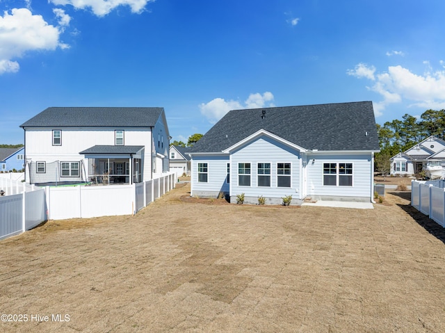 back of property with a lawn, a patio, a fenced backyard, a residential view, and roof with shingles